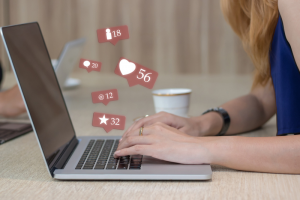 woman's hands typing with social icons popping out